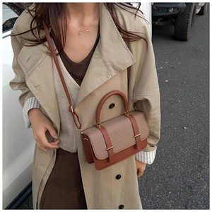 Close-up of stylish brown leather and khaki woven messenger bag on trench coat
