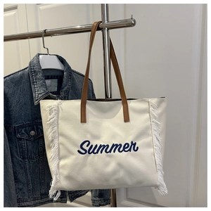 Détail du sac cabas en toile blanc cassé avec broderie Summer et franges blanches