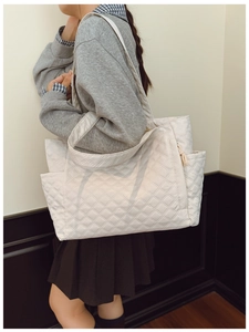 Detail showing side zipper pocket and quilted texture of a white tote shoulder bag