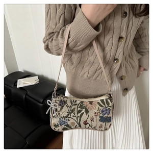 Detailed shot of retro floral woven fabric and elegant rhinestone bow charm on handbag