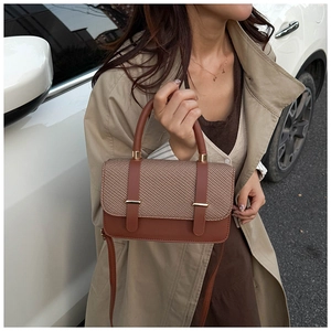 Brown leather and houndstooth crossbody bag detail shown with handle in outdoor setting