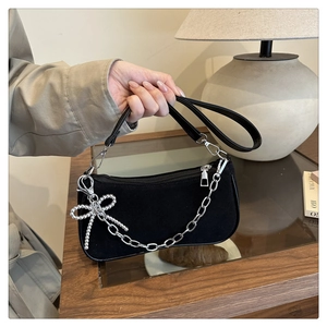 Detail of black suede underarm bag with silver chain and pearl bow pendant