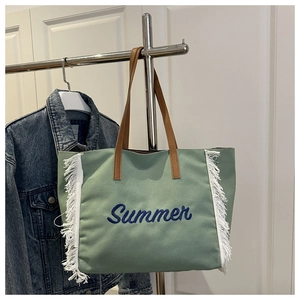 Détail du sac cabas en toile verte avec broderie Summer et bords à franges blanches