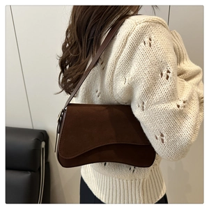 Detail of dark brown suede shoulder bag with unique wavy flap design for women