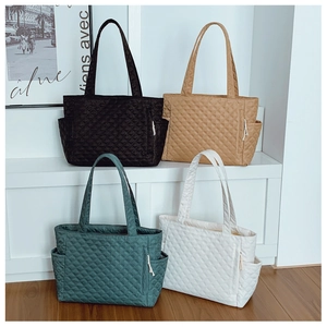 Close-up of quilted puffer tote bags in four colors on a white display stand
