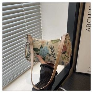 Detail of floral tapestry bag featuring silver bow charm and adjustable leather strap