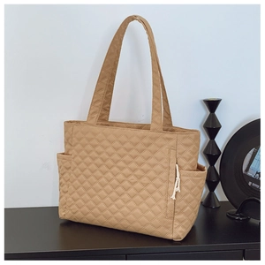 Close-up of khaki quilted tote bag featuring side drawstring detail and large pockets