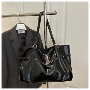 Close-up of black glossy PU tote bag with adjustable strap and metal buckle detail