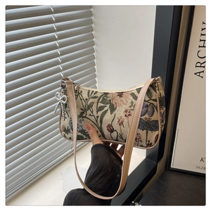 Detail view of woven floral embroidery tote bag with silver bow pendant and leather strap