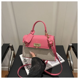 Detail of contrast stitching, metal twist lock, and pink leather on women's handbag