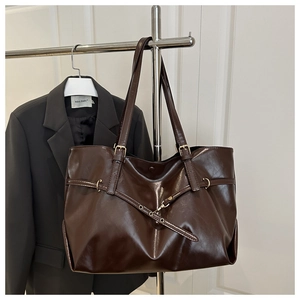 Detail of vintage brown leather tote bag with glossy finish and metal buckle straps