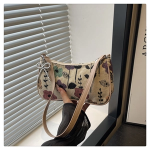 Detailed shot of beige floral fabric handbag with a silver bow chain accessory