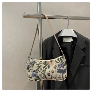 Detail of vintage jacquard baguette bag with colorful floral embroidery and bow charm