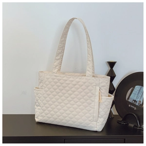 Close-up of beige quilted tote bag showing diamond stitching and side pocket detail