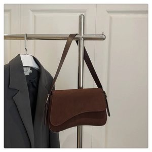 Detail of dark brown faux suede underarm bag with curved flap and metal strap rings