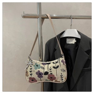 Detail of floral jacquard underarm bag with elegant pearl bow charm on a hanger