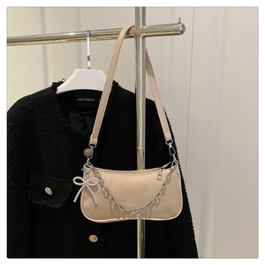 Detail of beige matte leather shoulder bag with silver chain and pearl bow charm