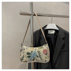 Detailed close-up of floral jacquard crescent bag with silver beaded bow charm