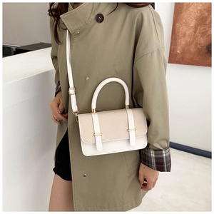 Detail of cream woven handbag with gold buckles worn over a green trench coat