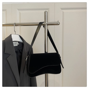Close-up of black suede underarm bag with wave flap design and gold hardware detail