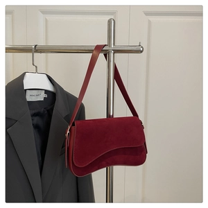 Detail view of burgundy suede shoulder bag showing smooth texture and flap closure design