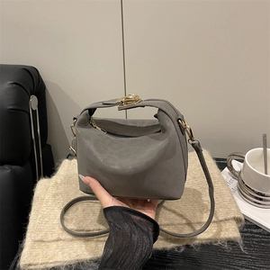 Elegant grey mini crossbody bag with gold buckle on a cozy indoor background