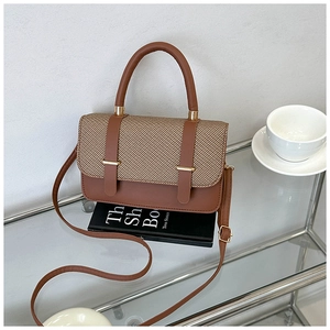 Detail of trendy two-tone crossbody messenger bag with metallic hardware on a display shelf