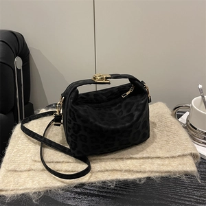 Schwarze Handtasche mit Leopardenmuster, Goldverschluss und Schultergurt auf Strickstoff