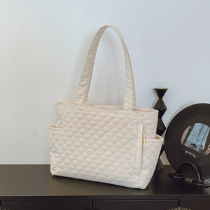 White quilted tote bag with large capacity and side pockets on a minimalist background