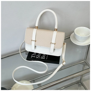 Detail of elegant contrast panel handbag with woven texture and gold metal hardware