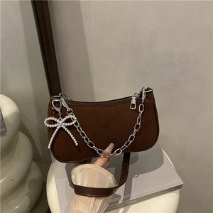 Dark brown matte suede underarm bag with silver chain and pearl bow detail on books