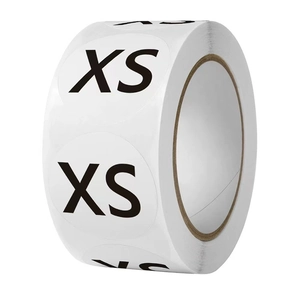 Detail view of round white size stickers roll with bold black XS text for clothing labeling