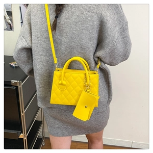 Détail d'un sac jaune matelassé avec pochette assortie sur une tenue en maille grise