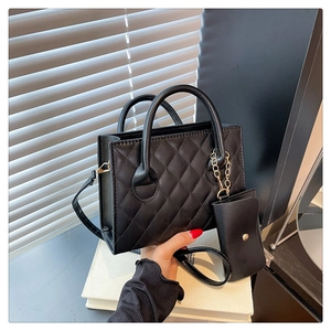 Détail du sac cabas matelassé noir avec mini pochette à chaîne dorée et finition en PU