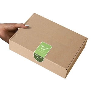 Kraftpapierbox mit grünem 'Thank You' Smiley Aufkleber auf weißem Hintergrund