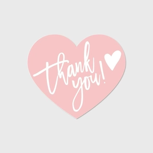 Detailed view of a pink heart-shaped thank you sticker with white handwritten lettering