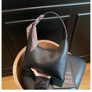 Detail of black leather hobo bag with a decorative silk scarf tied on the handle strap