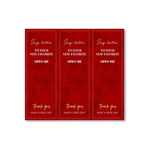 Macro view of red rectangular waterproof stickers with gold foil OPEN ME and floral texture