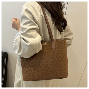 Detailed shoulder view of a leopard print tote bag with brown leather straps and gold logo