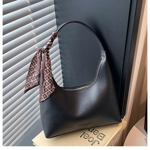 Detail of black leather hobo bag featuring a decorative silk scarf on the shoulder strap