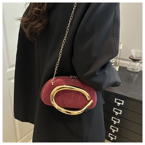 Burgundy velvet round clutch bag with metal ring detail and gold chain strap shown on model