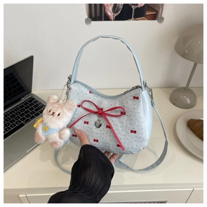 Détail du sac bleu clair avec imprimés nœuds rouges et décoration de pendentif en cœur