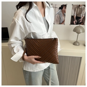 Close-up of brown PU leather envelope clutch featuring V-shaped metal rivet detailing