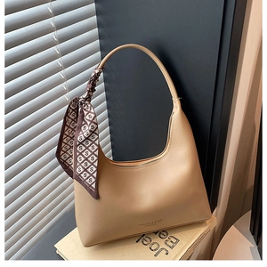 Detail of beige hobo shoulder bag with matte leather finish and decorative silk scarf