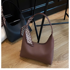 Détail du sac à main en cuir marron grainé avec un foulard en soie décoratif sur l'anse