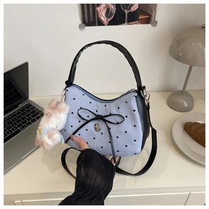 Détail du sac à rayures bleues avec motifs de cœurs, nœud noir et charm peluche doux