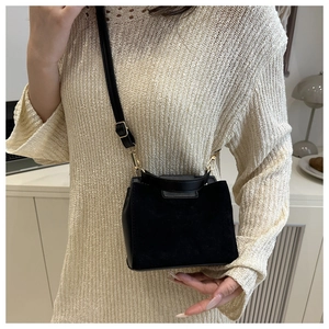 Detail of black leather and suede bag showing gold hardware and top handle for women