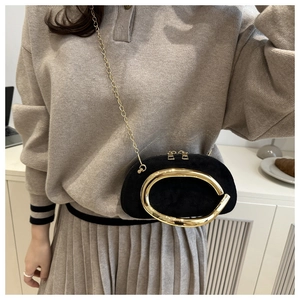Close-up of black suede evening bag with golden ring hardware and metal chain strap