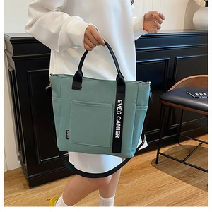Detail of mint green canvas lunch bag with EVES CAMIER lettering and adjustable black strap