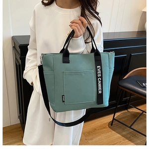 Detail of mint green lunch bag with black adjustable shoulder strap and side sport tag